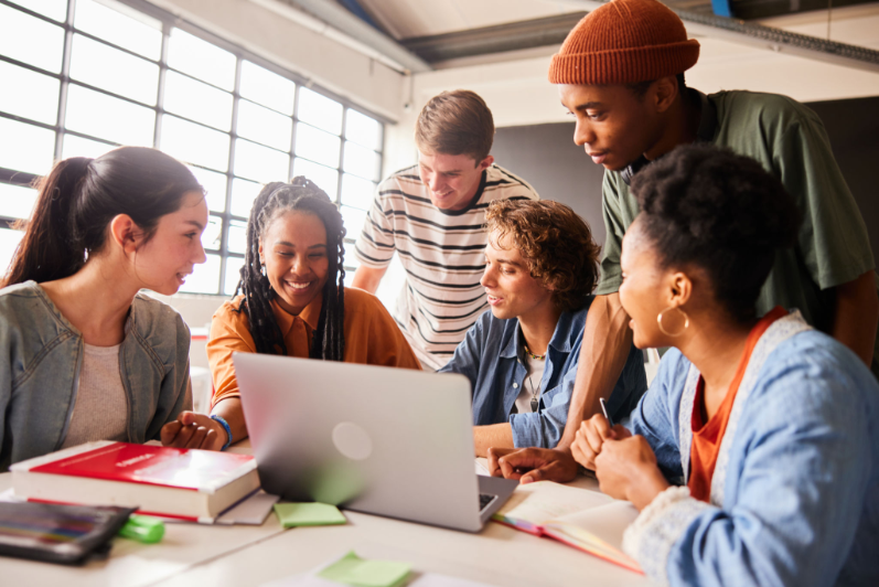 Group of people collaborating around a laptop.